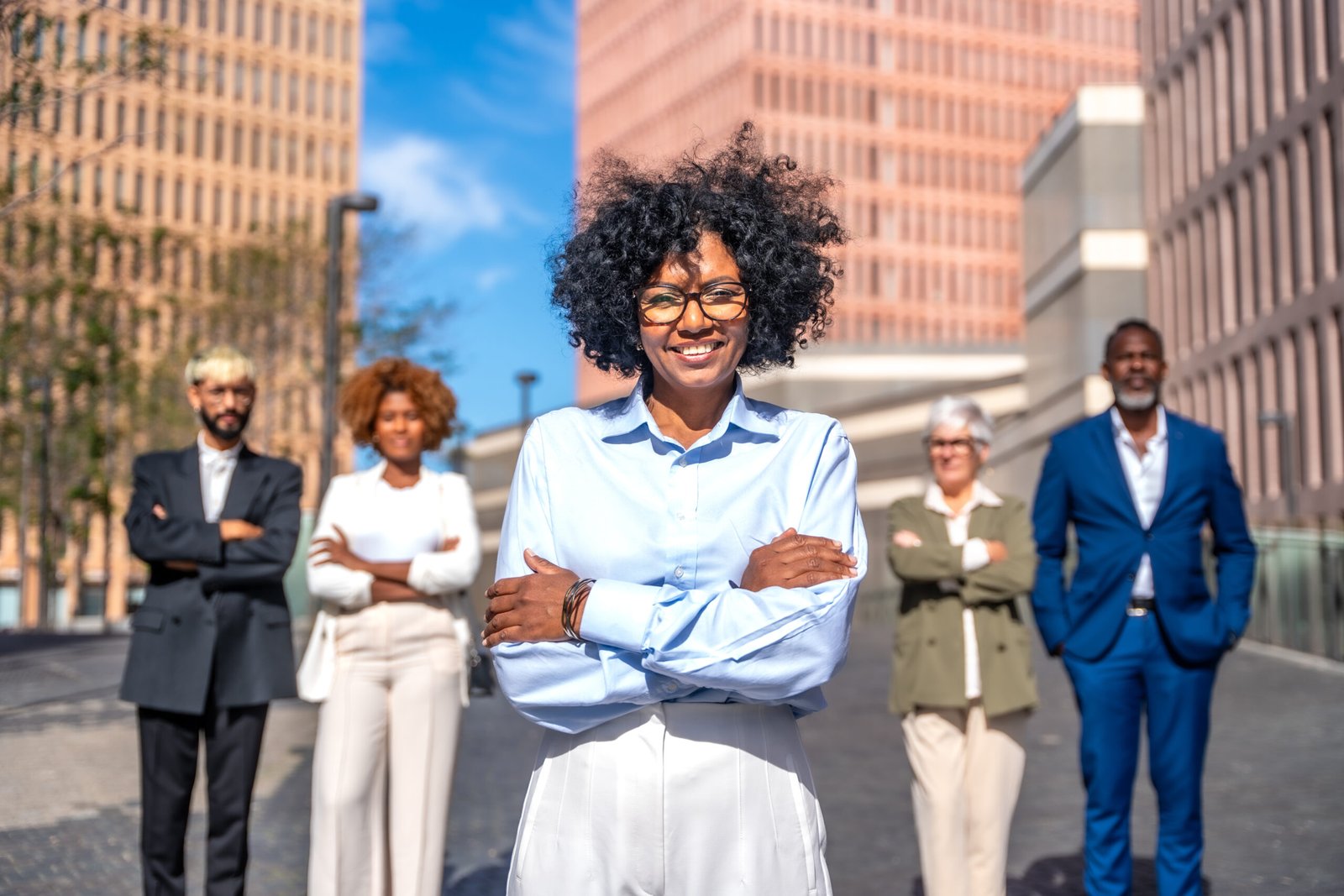 Frontal portrait of a happy entrepreneur standing proud next to her team in the city street